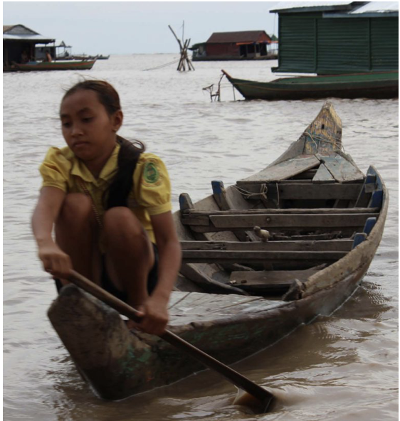 An image of a Vietnamese girl rowing her boat to visit her friends living in houseboats in Tonle Sap Lake in Cambodia