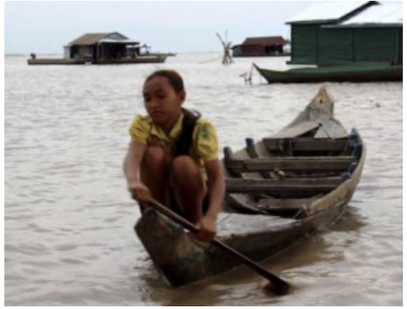 An image of little girl on Tonle Sap Lake in Cambodia rowing her boat to visit her friends.