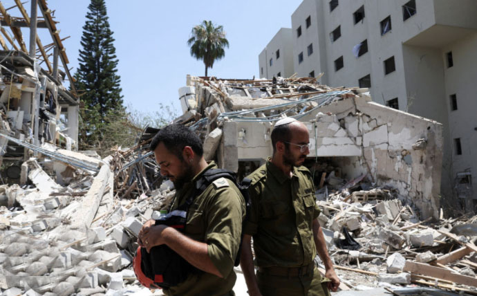 Israeli soldiers examine damage after rocket bomb exploded on a building in Tel Aviv
