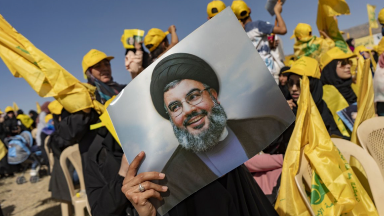 Hezbollah people cheering and holding image of their leader in their fight against Israel